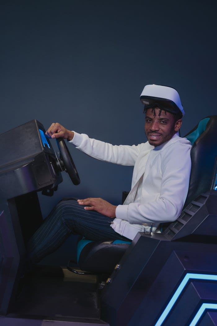 A man wearing a VR headset interacting with a racing simulator in an indoor arcade setting.