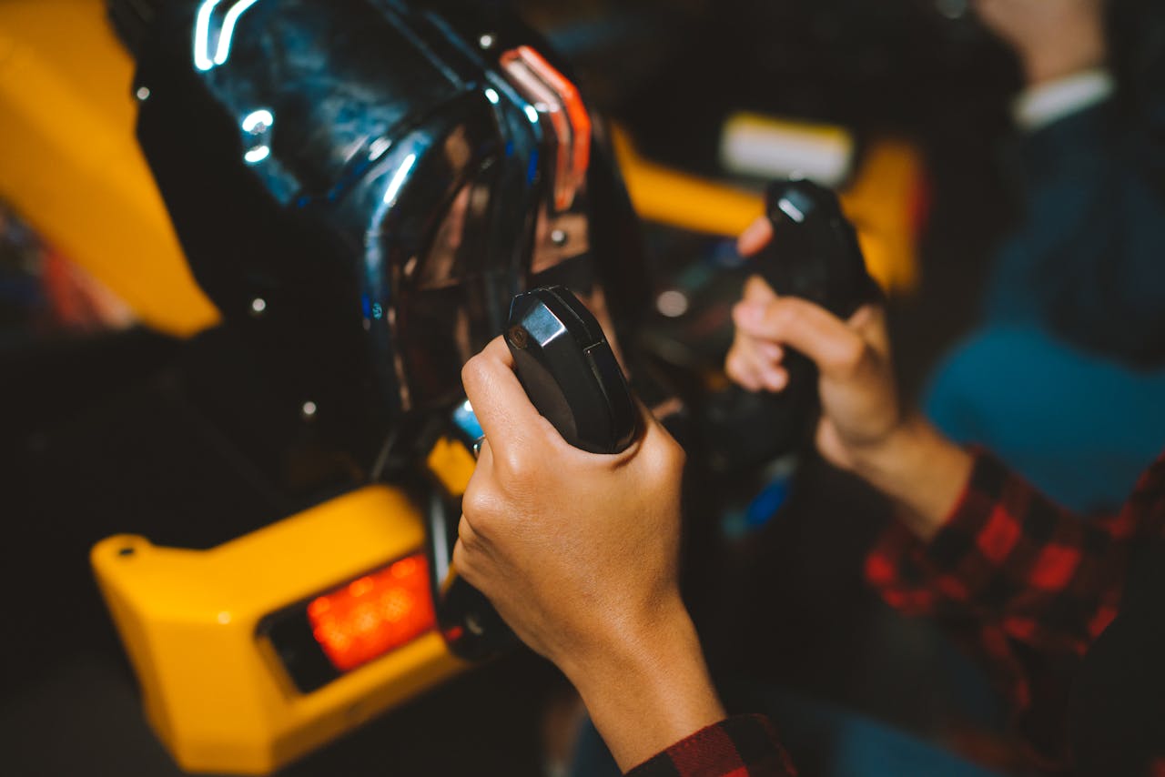 Close-up shot of hands gripping arcade game controllers, showcasing an immersive gaming experience indoors.